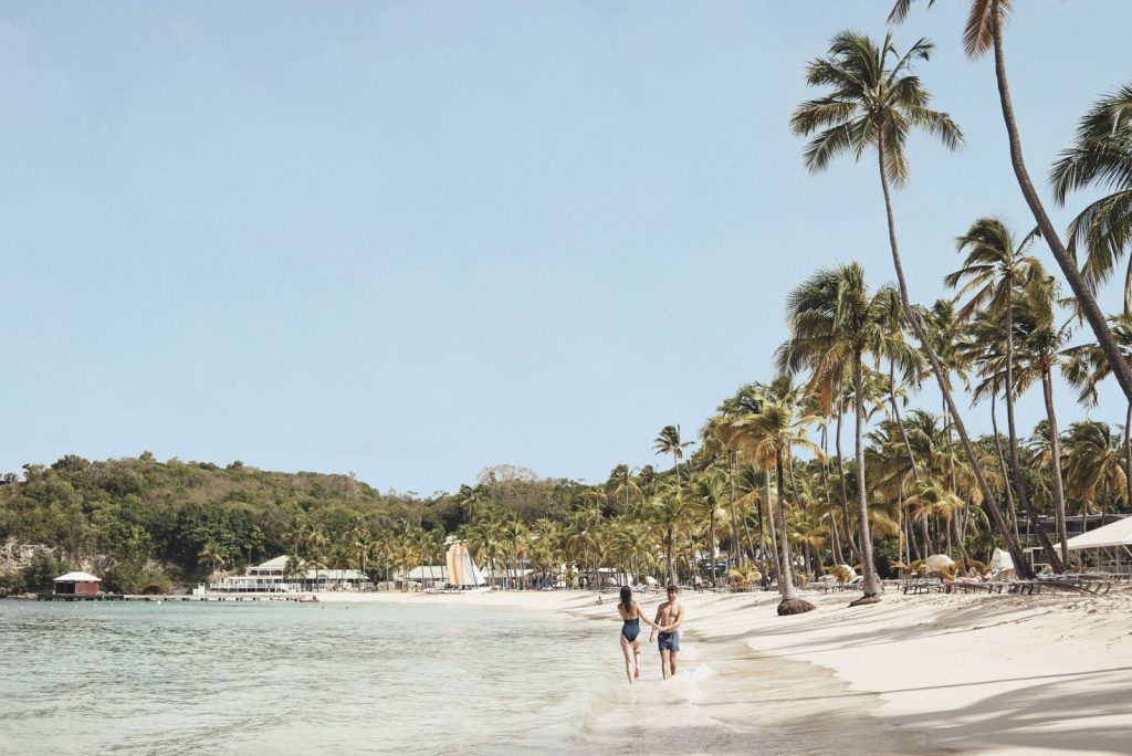 Couple qui marche au bord de l’eau sur la plage du Club Med La Caravelle, en Guadeloupe
